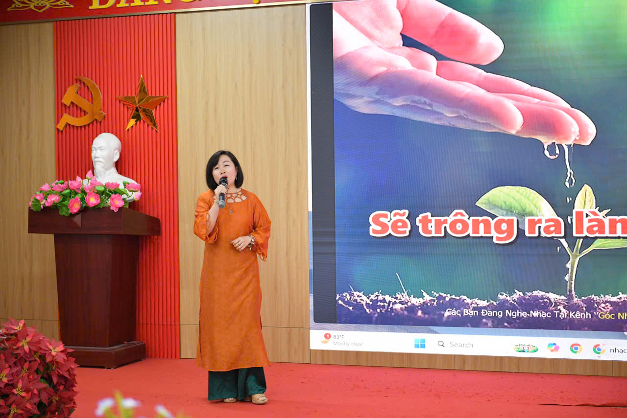 A person in orange dress speaking into a microphone
Description automatically generated