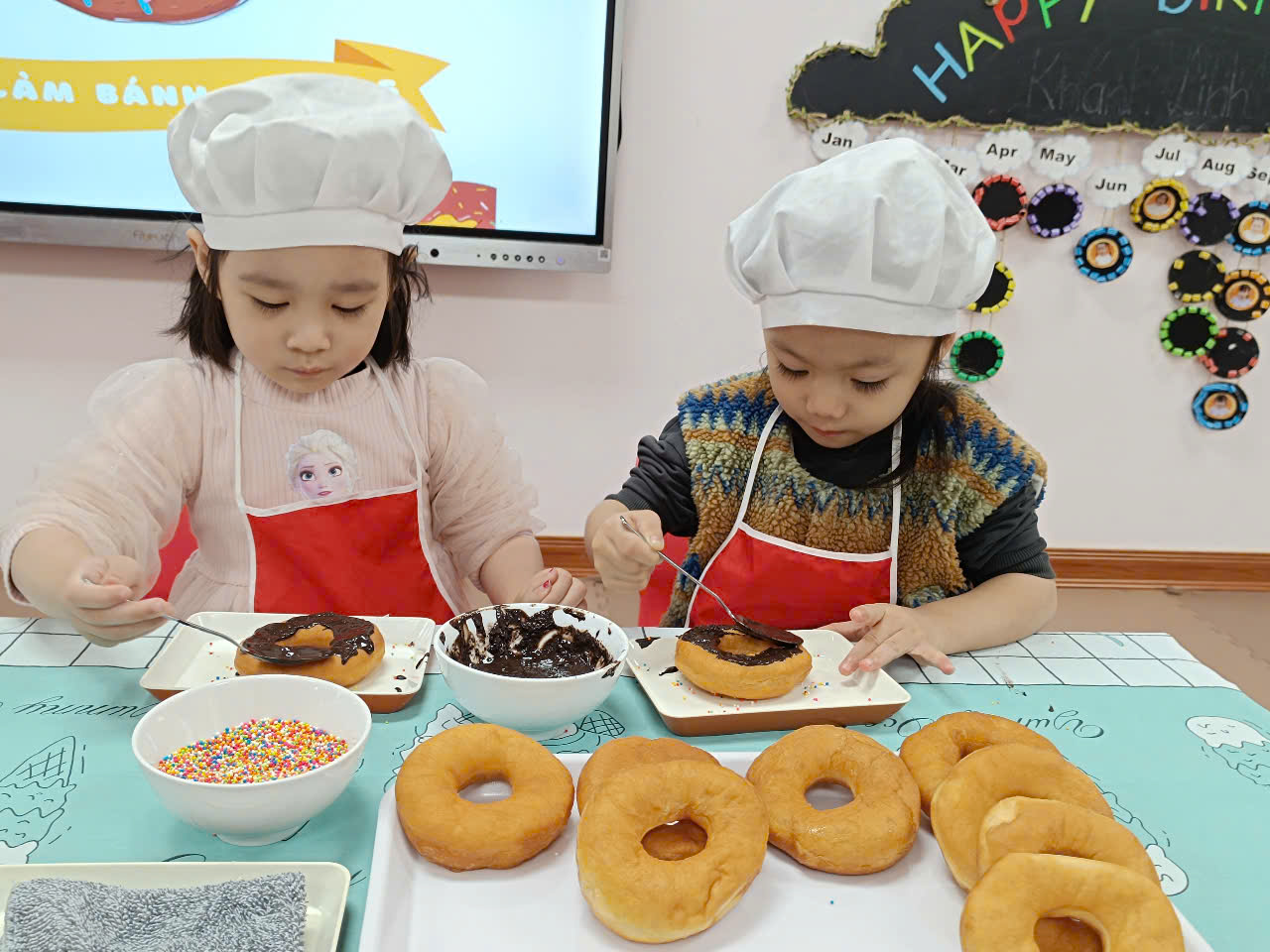 Two girls wearing chef hats and cooking doughnuts
Description automatically generated